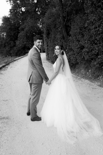 Couple de mariés se tenant la main sur un chemin, en noir et blanc