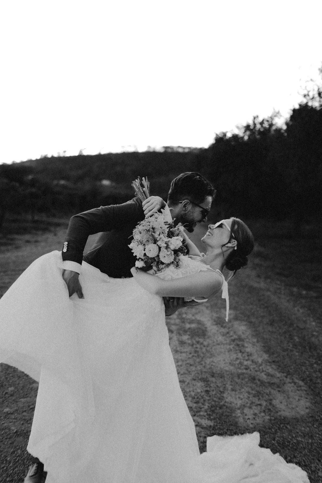 Couple de mariés riant dans un jardin, en noir et blanc