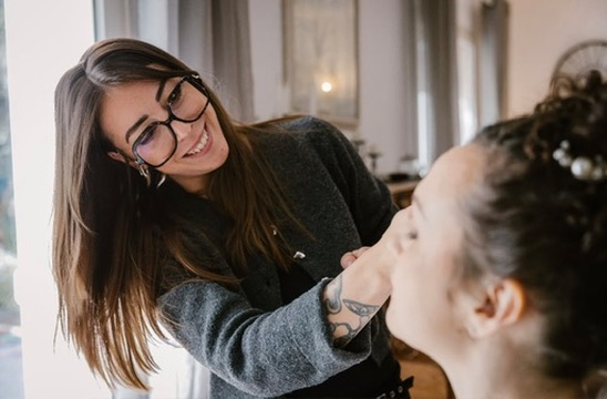 Laura sourit en maquillant une cliente