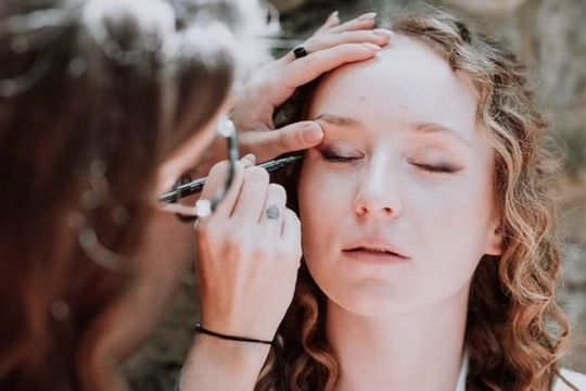Laura maquille le regard d’une future mariée aux cheveux bouclés