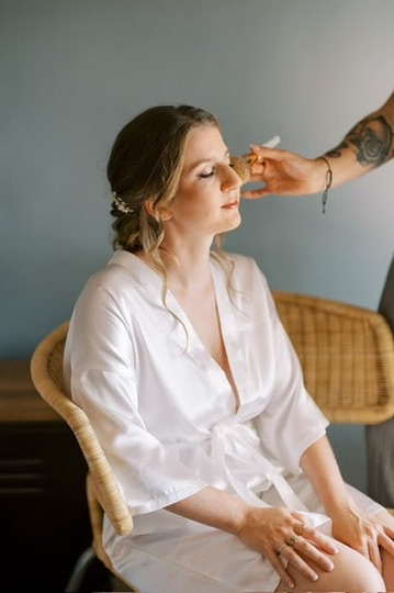 Cliente assise en peignoir blanc pendant la préparation de son maquillage
