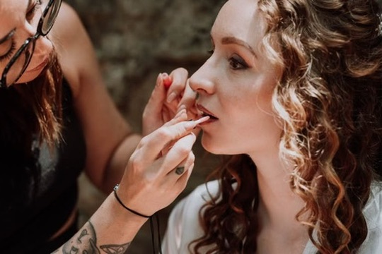 Laura retouche les lèvres d’une future mariée aux cheveux bouclés
